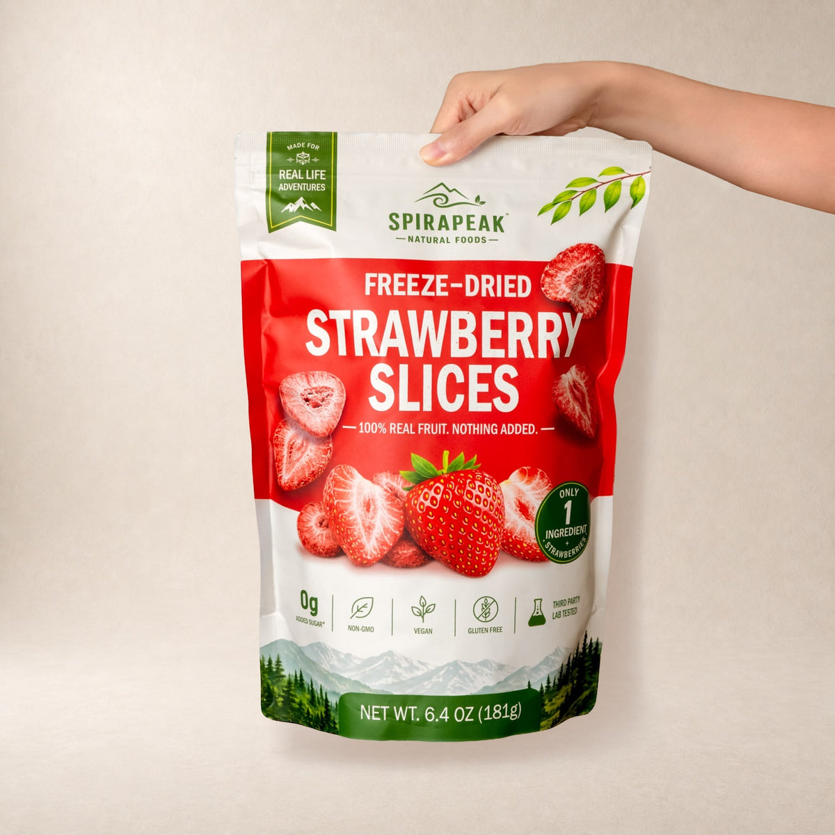 A hand holding the SPIRAPEAK 6.4 oz (181 g) resealable strawberry pouch against a warm background.
